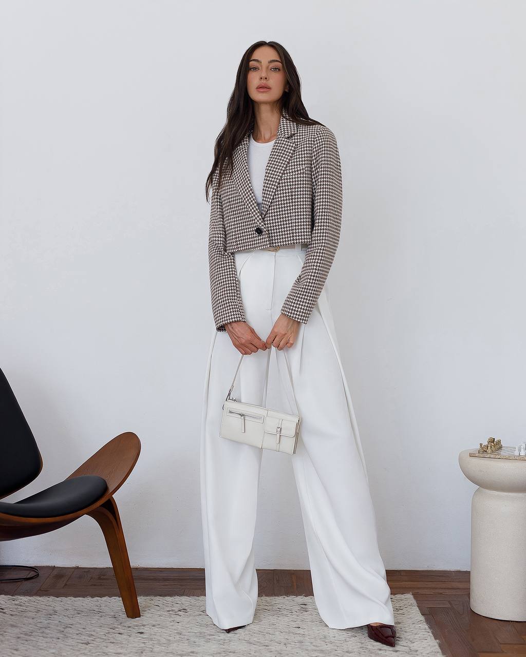 Woman wearing a checkered blazer and white pants in an indoor setting.