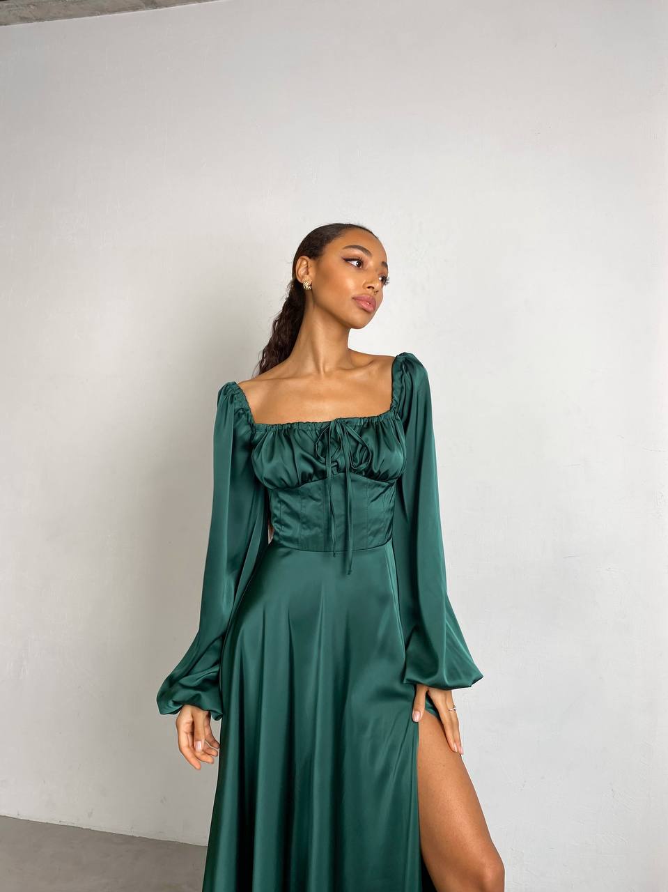 Woman wearing a green dress with long sleeves against a white background