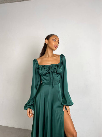 Woman wearing a green dress with long sleeves against a white background