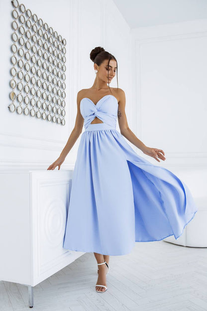 Woman wearing a light blue dress with a unique bodice design in a minimalistic room.