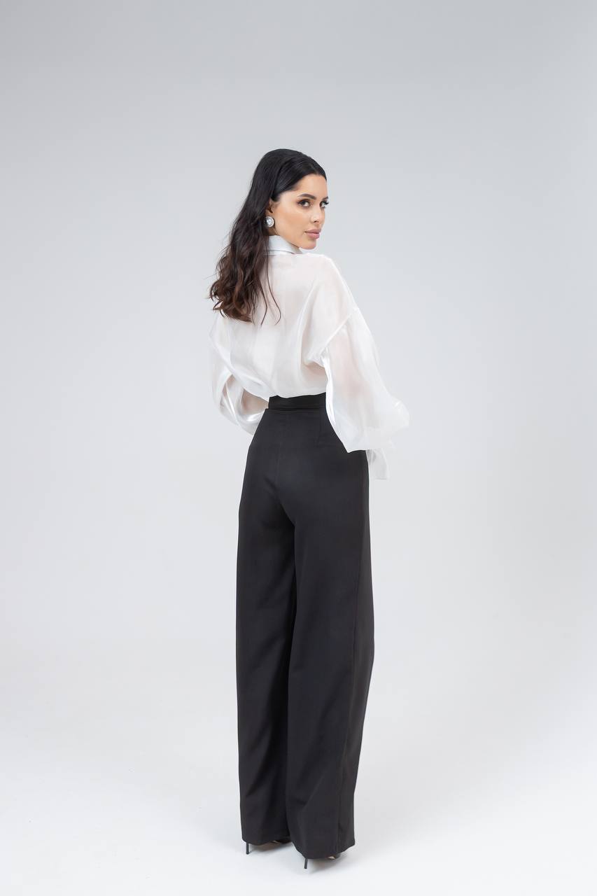Woman wearing a white blouse and black high-waisted pants on a white background