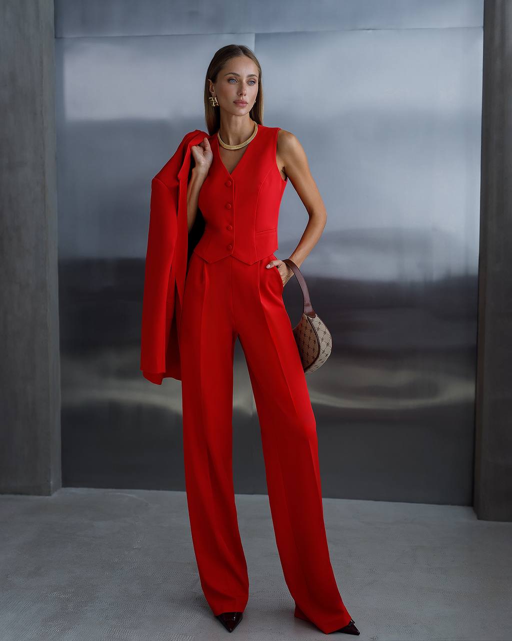 Woman in a red outfit standing against a gray background
