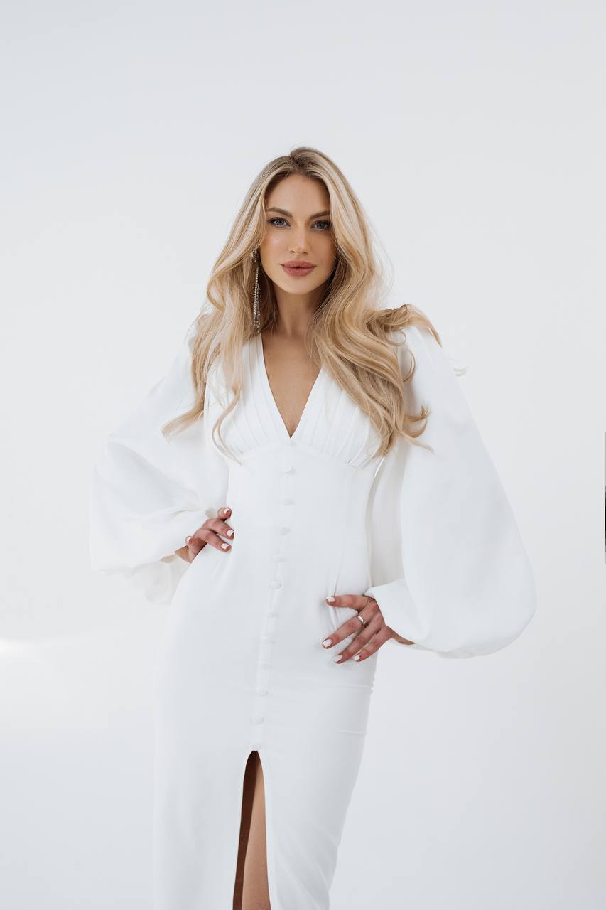 Woman wearing a white dress with bell sleeves against a white background