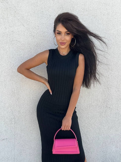 Woman in a black dress holding a pink handbag against a light gray background