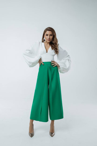 Woman wearing a white blouse and green pants on a white background