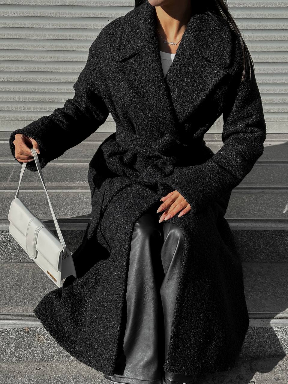 Person wearing a long black coat with a white background