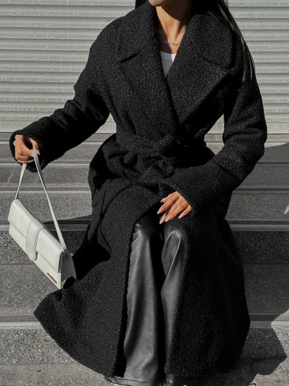 Person wearing a long black coat with a white background