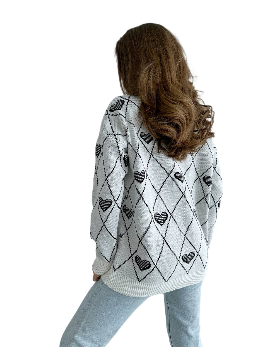 Person wearing a white sweater with black heart patterns on a white background