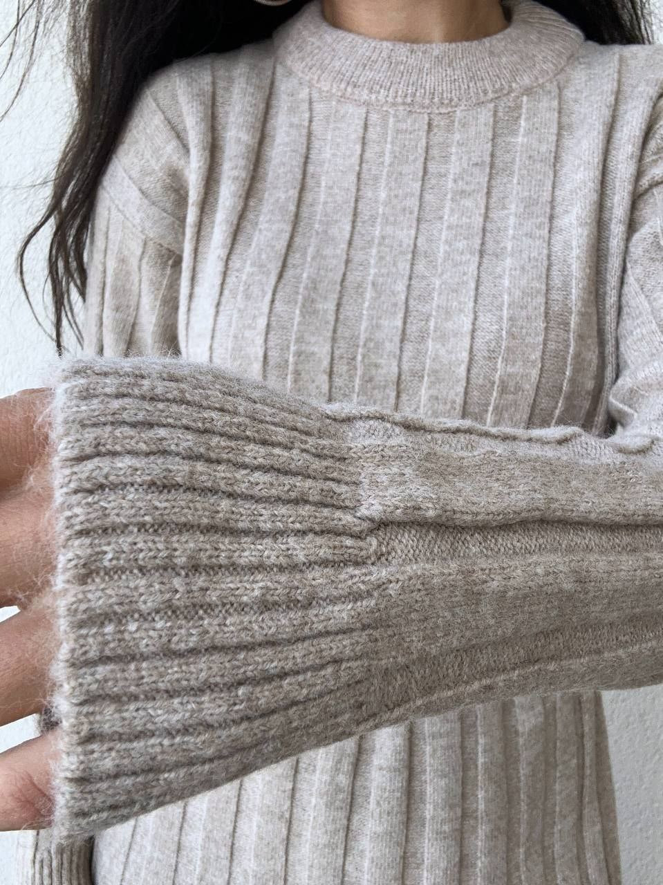 Close-up of a person wearing a beige sweater with a white background