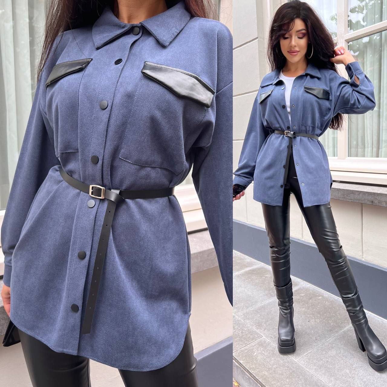 Woman wearing a blue coat with black accents and black leather pants outdoors.