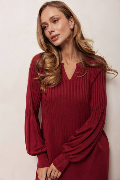 Woman wearing a burgundy ribbed dress against a plain background