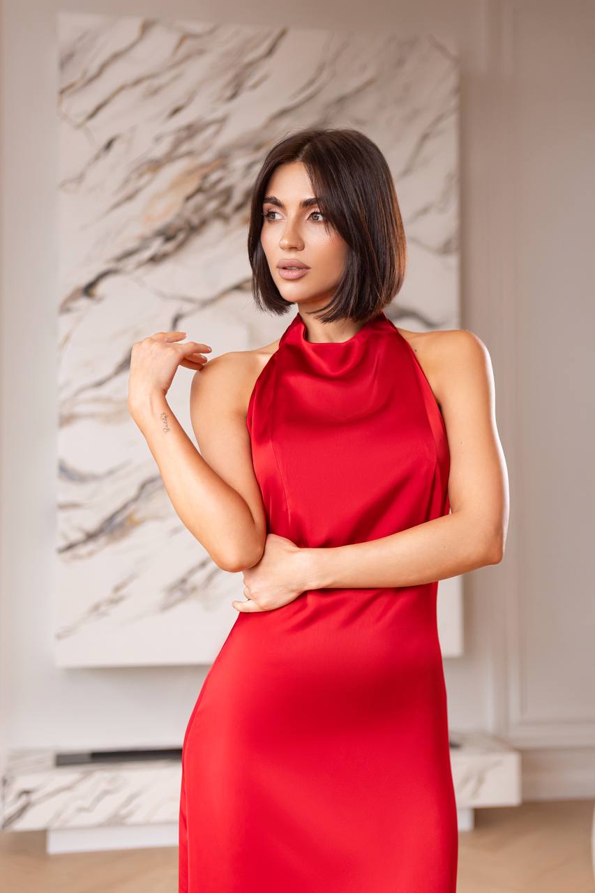 Woman wearing a red dress standing in a room with a marble wall.