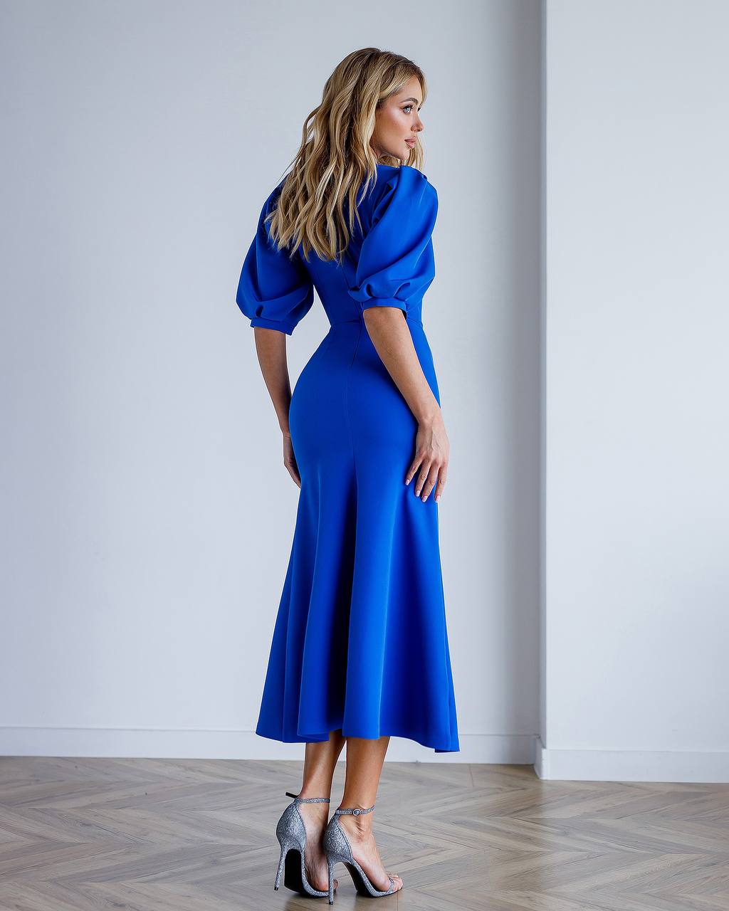 Woman wearing a blue dress with puffed sleeves in a minimalistic setting