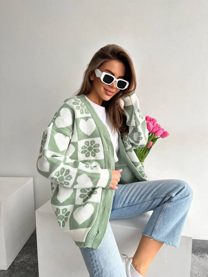 Woman wearing a green patterned cardigan holding pink tulips against a white background