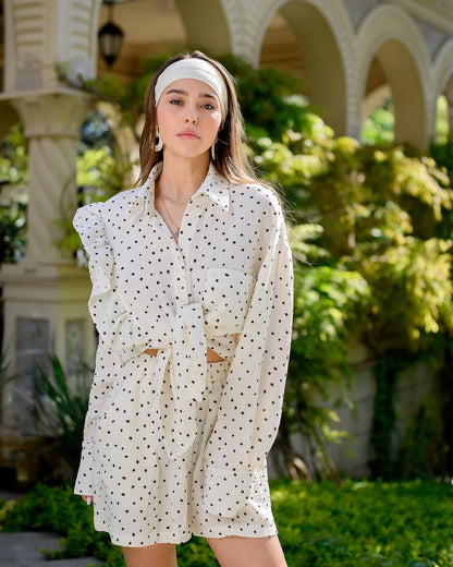 Woman wearing a white polka dot dress with a headband in an outdoor setting