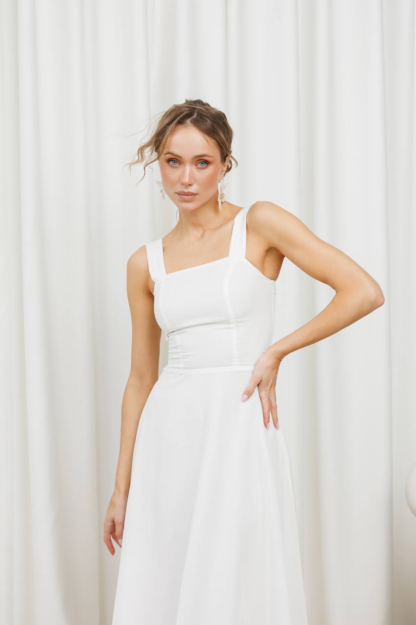 Woman wearing a white dress against a white curtain background