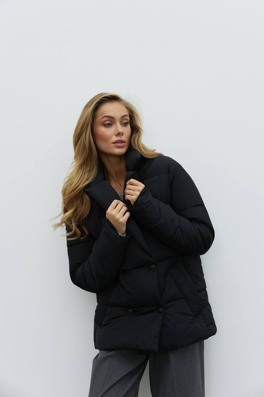 Woman wearing a black puffer jacket against a white background
