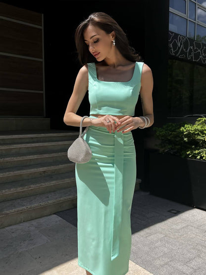 Woman in a light green dress standing outdoors near steps.