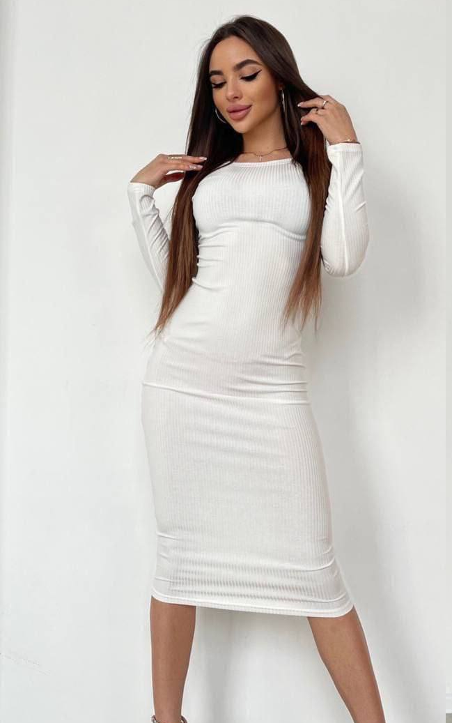 Woman wearing a white long-sleeve dress against a plain background