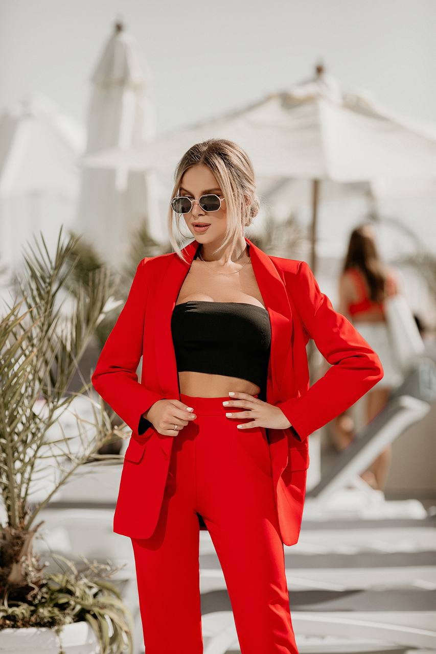 Woman in a red suit standing outdoors with blurred background