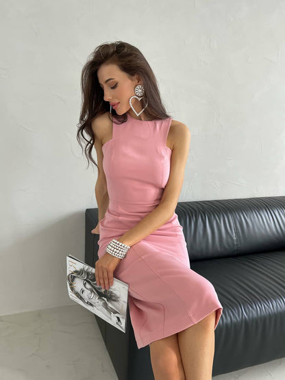 Woman in a pink dress holding a clutch against a neutral background