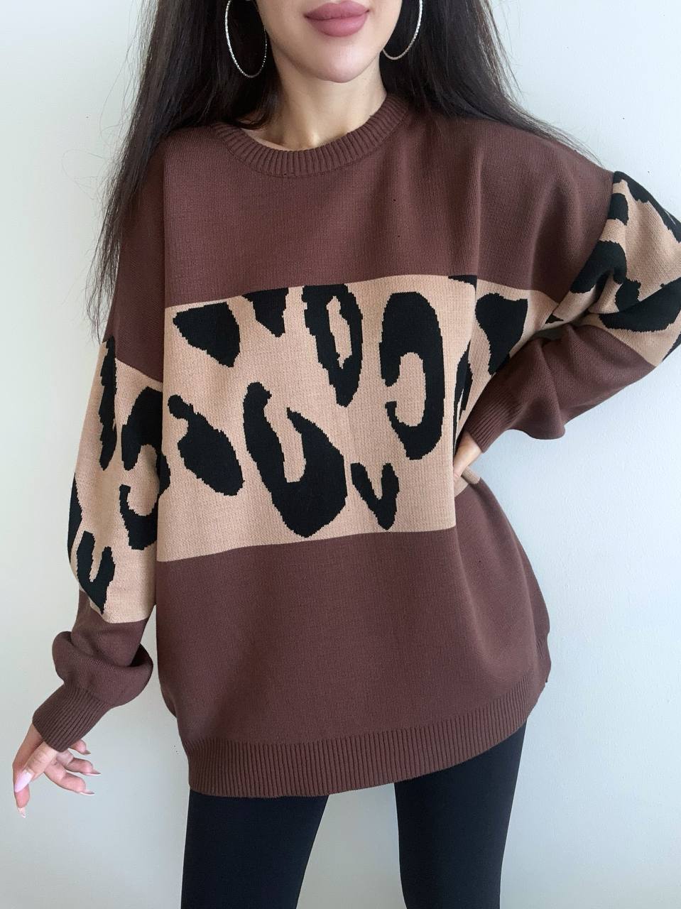 Brown sweater with leopard print pattern worn by a person against a white background