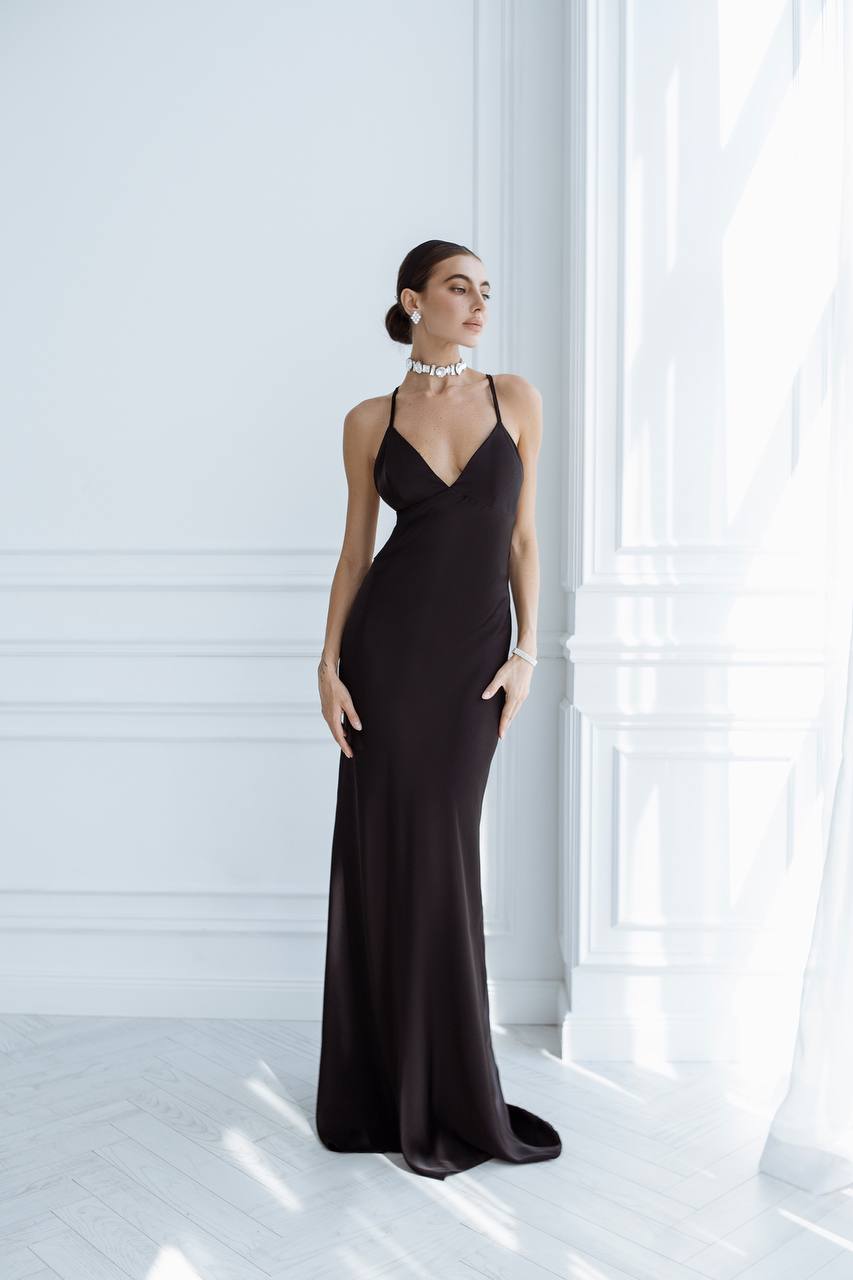 Woman wearing a black evening gown in a bright room with white walls and floor.