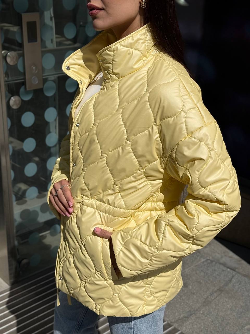 Person wearing a yellow quilted jacket with a blurred background