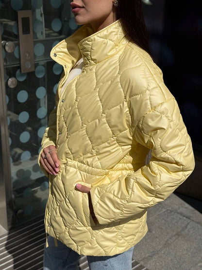 Person wearing a yellow quilted jacket with a blurred background