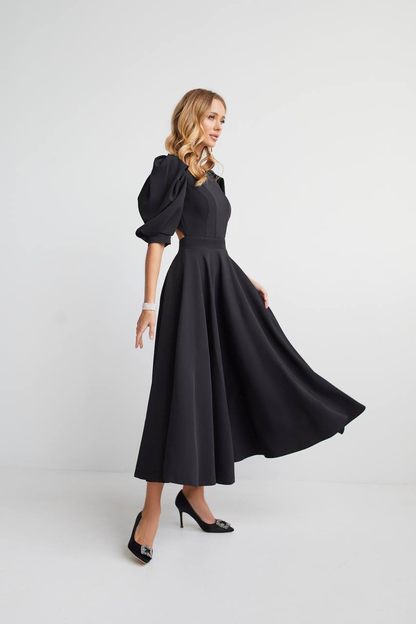 Woman wearing a black dress with puff sleeves on a white background