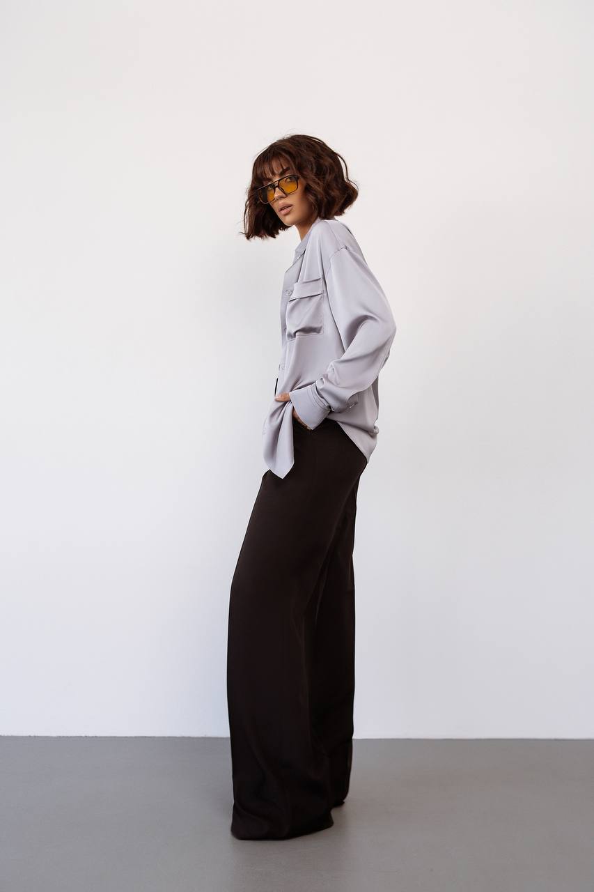 Person wearing a light gray oversized shirt and black wide-leg pants against a white background