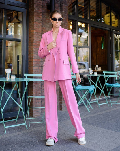 Woman in a pink suit standing outdoors near a cafe.