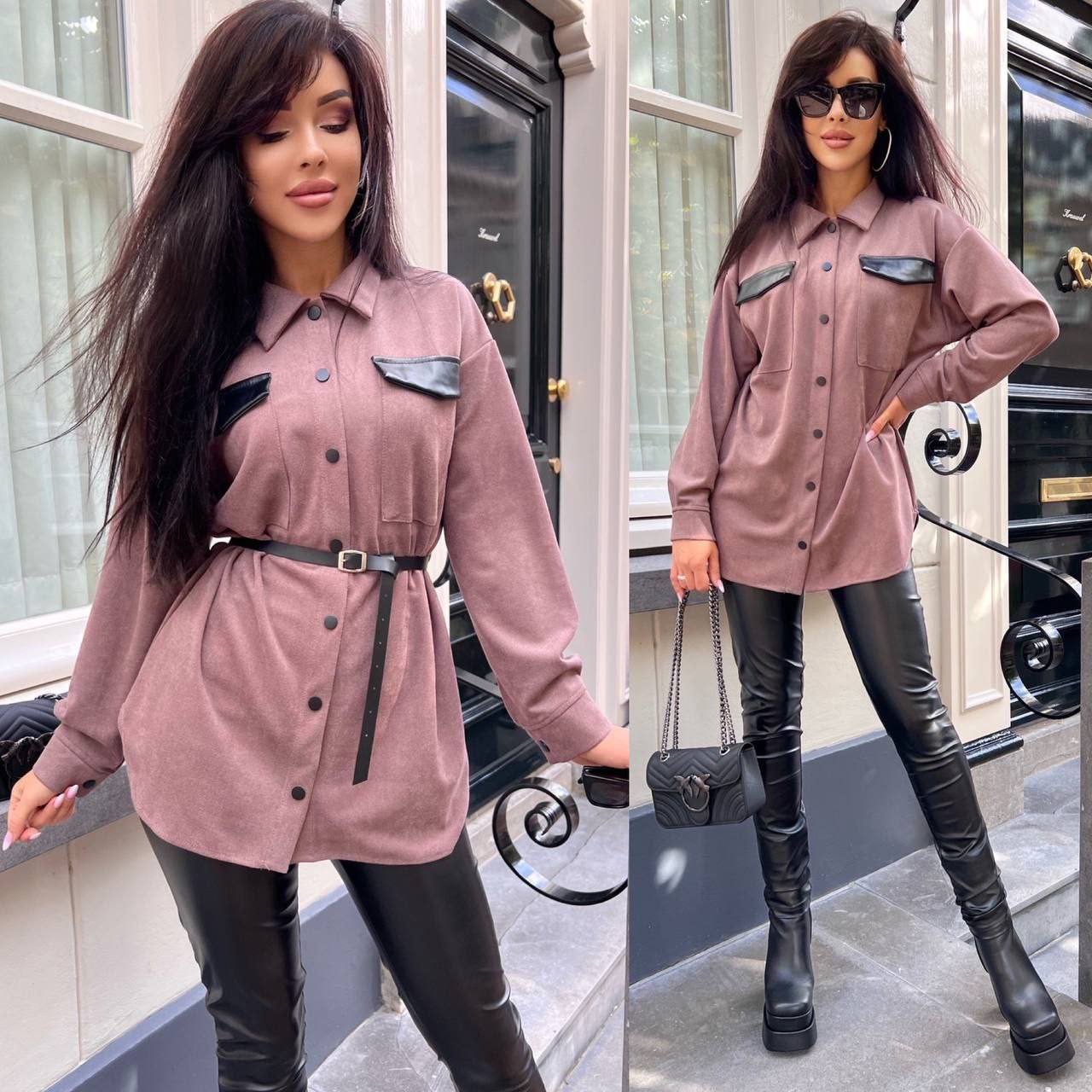 Woman wearing a pink shirt dress with black accents and black leather pants in an urban setting.