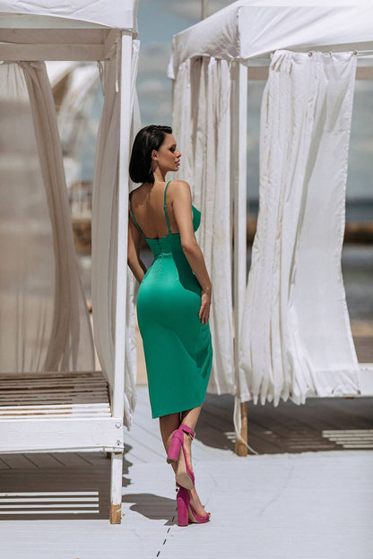 Woman in a green dress standing between white canopies on a bright day.