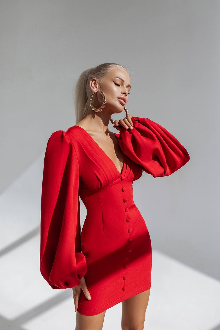 Woman wearing a red dress with puff sleeves against a gray background