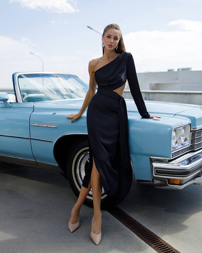 Woman in a black dress standing next to a blue vintage car on a rooftop.