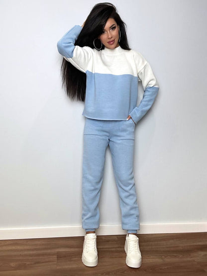 Person wearing a two-tone blue and white outfit with white sneakers against a plain background
