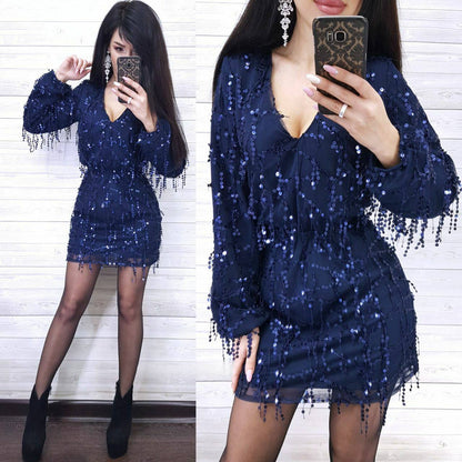 Woman wearing a blue sequin dress with long sleeves and fringe details, taking a mirror selfie.