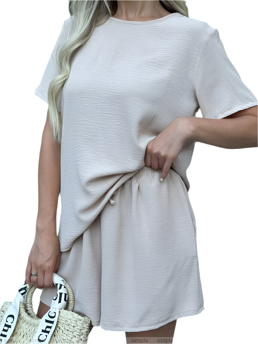 Woman wearing a light gray dress holding a straw bag with 'Chic' text on a white background