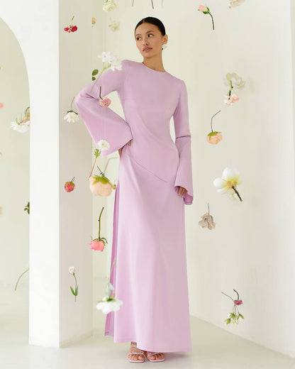 Woman wearing a long, light purple dress with floral decorations in the background