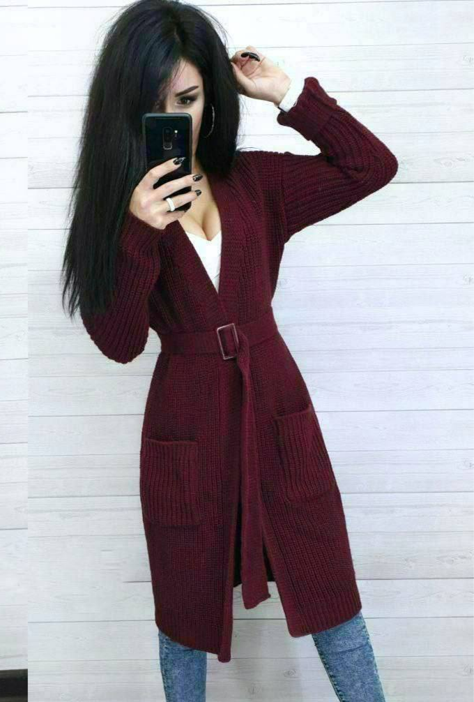 Person wearing a burgundy cardigan taking a mirror selfie against a white wall.