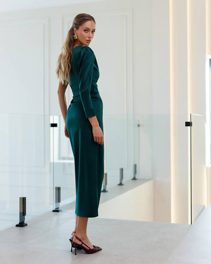 Woman in a green dress standing in a modern interior setting