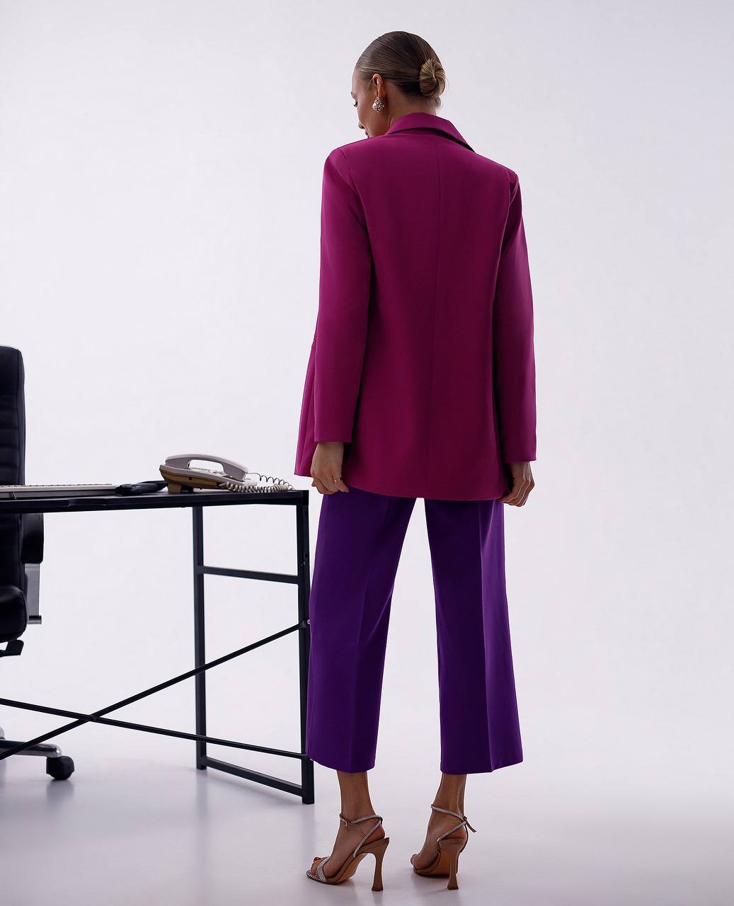 Person wearing a purple suit standing in an office setting.