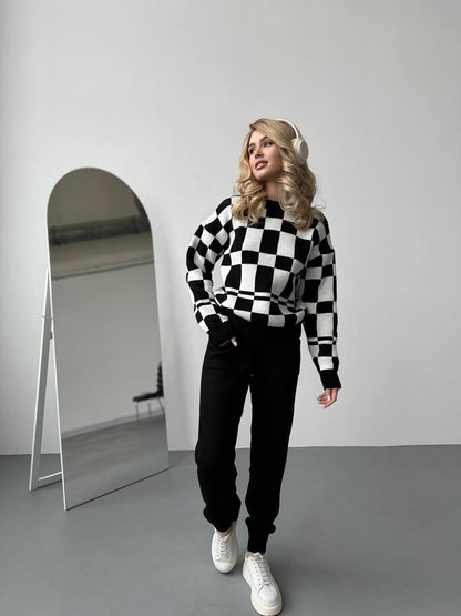 Person wearing a black and white checkered sweater with a mirror in the background