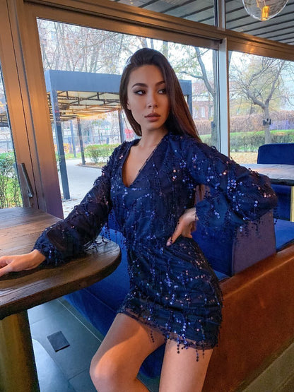 Woman in a blue sequin dress posing indoors.