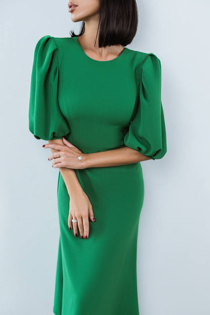 Green dress with puffed sleeves worn by a person on a light gray background
