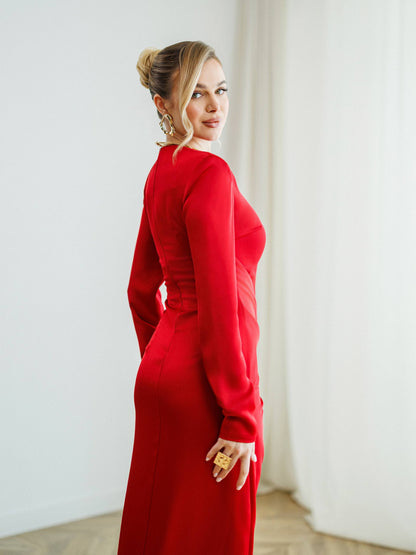 Woman wearing a red dress standing against a white wall.