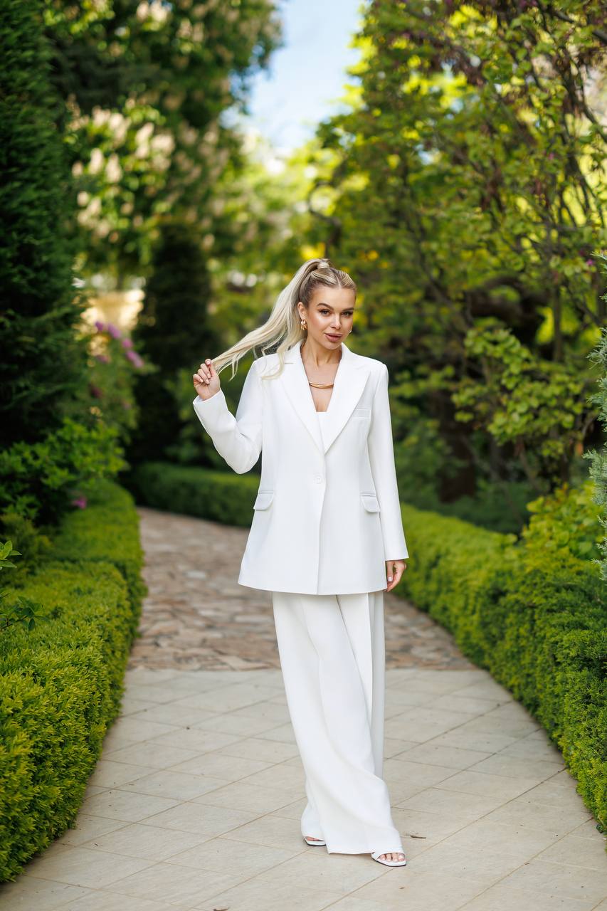 Woman in a white suit walking on a path with greenery around