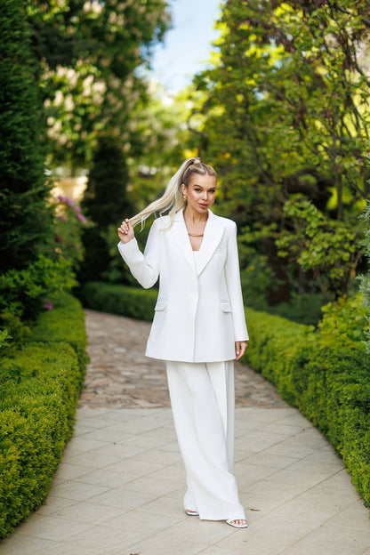 Woman in a white suit walking on a path with greenery around