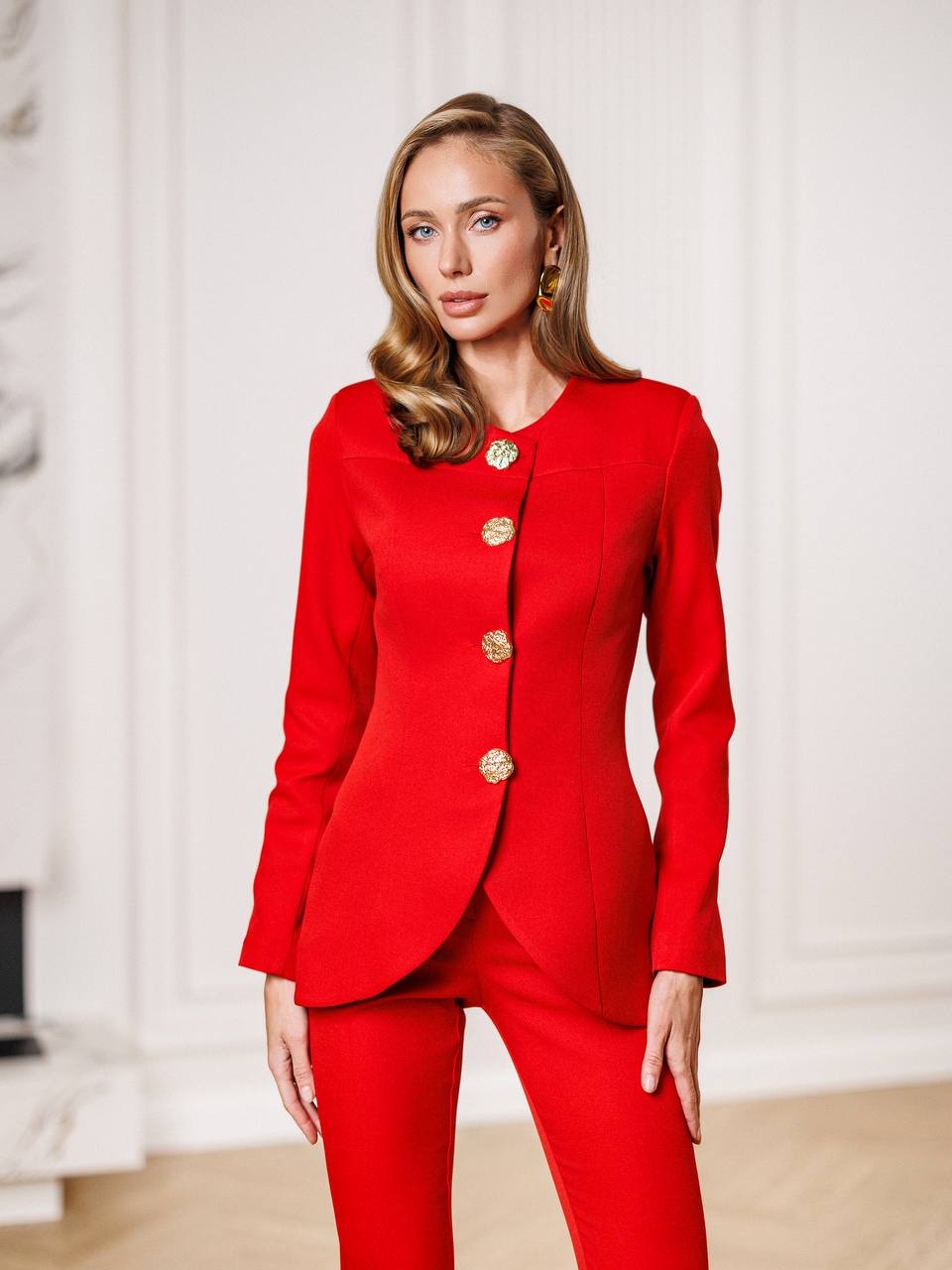Woman wearing a red suit with gold buttons in an indoor setting